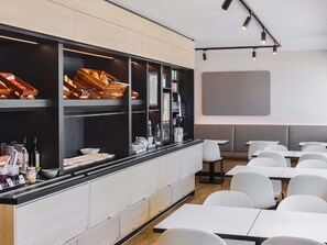 A modern restaurant with a long counter, white chairs, and a large screen on the wall.