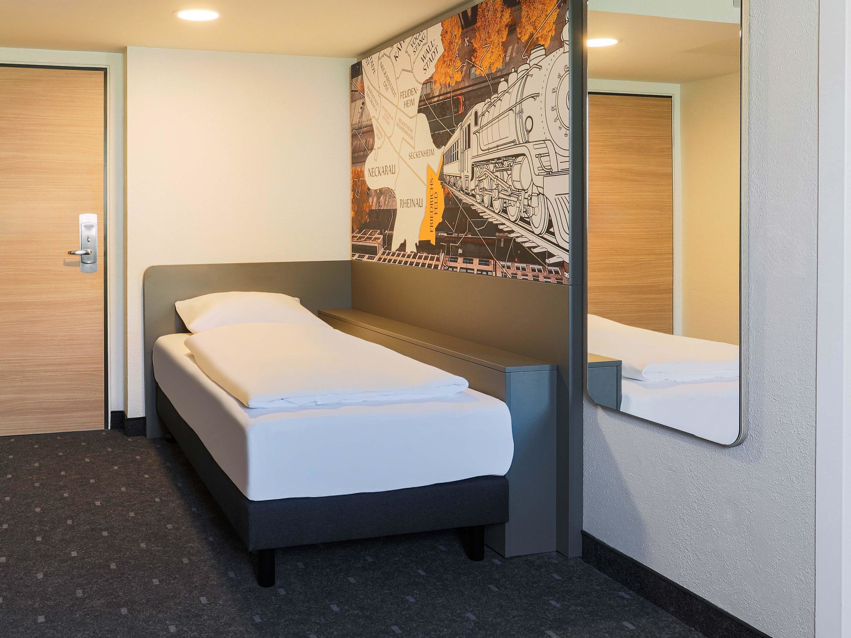 Ein Hotelzimmer mit Bett, Kopfteil, Wandspiegel und Tür.
