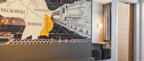 A hotel room with a bed, a wall map, and a lamp.