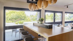 Una cocina moderna con una isla de madera, taburetes de bar, ventanas amplias e iluminación colgante.