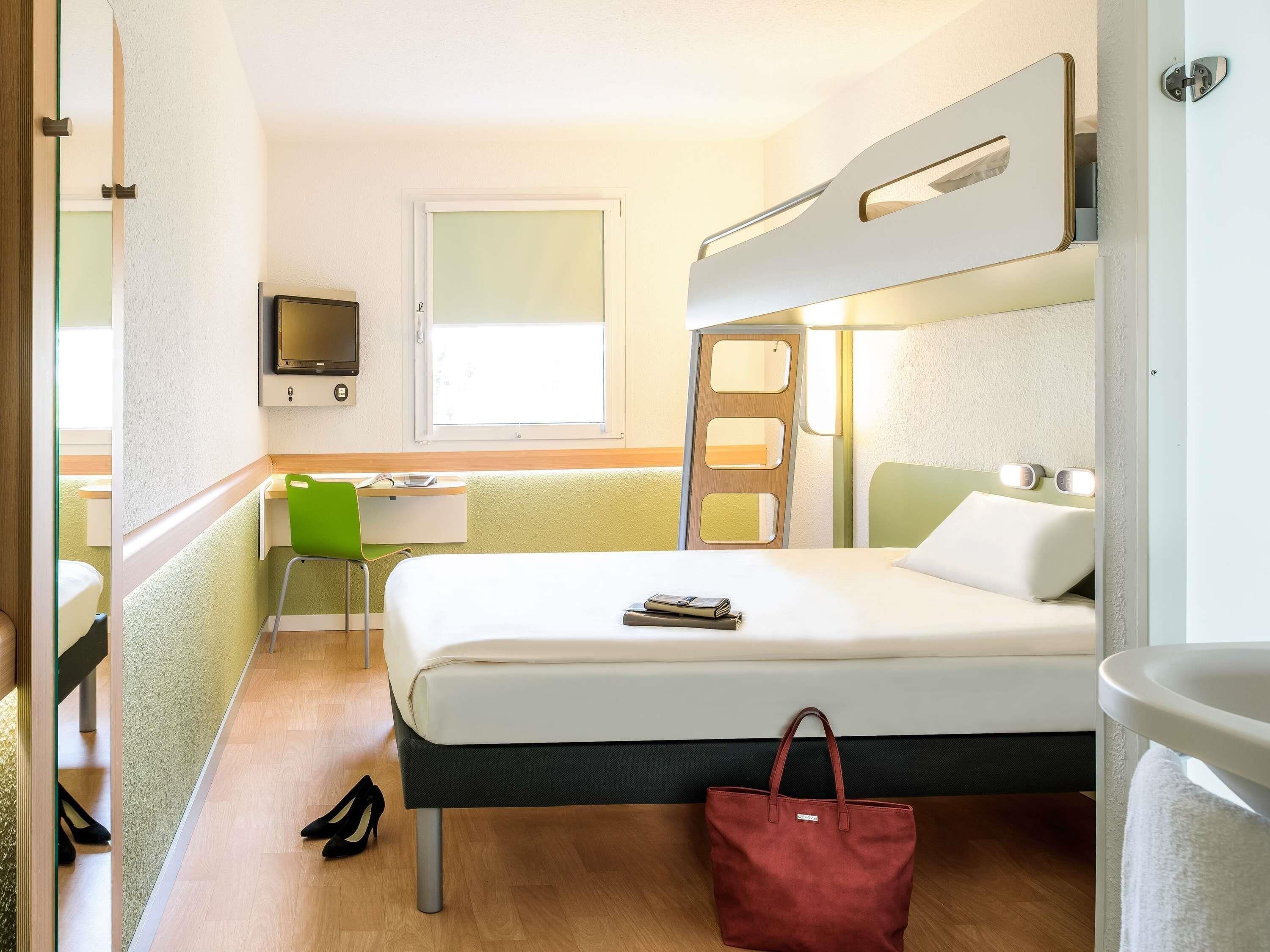 Ein Hotelzimmer mit Bett, Schreibtisch, Stuhl, Fernseher und Bad.