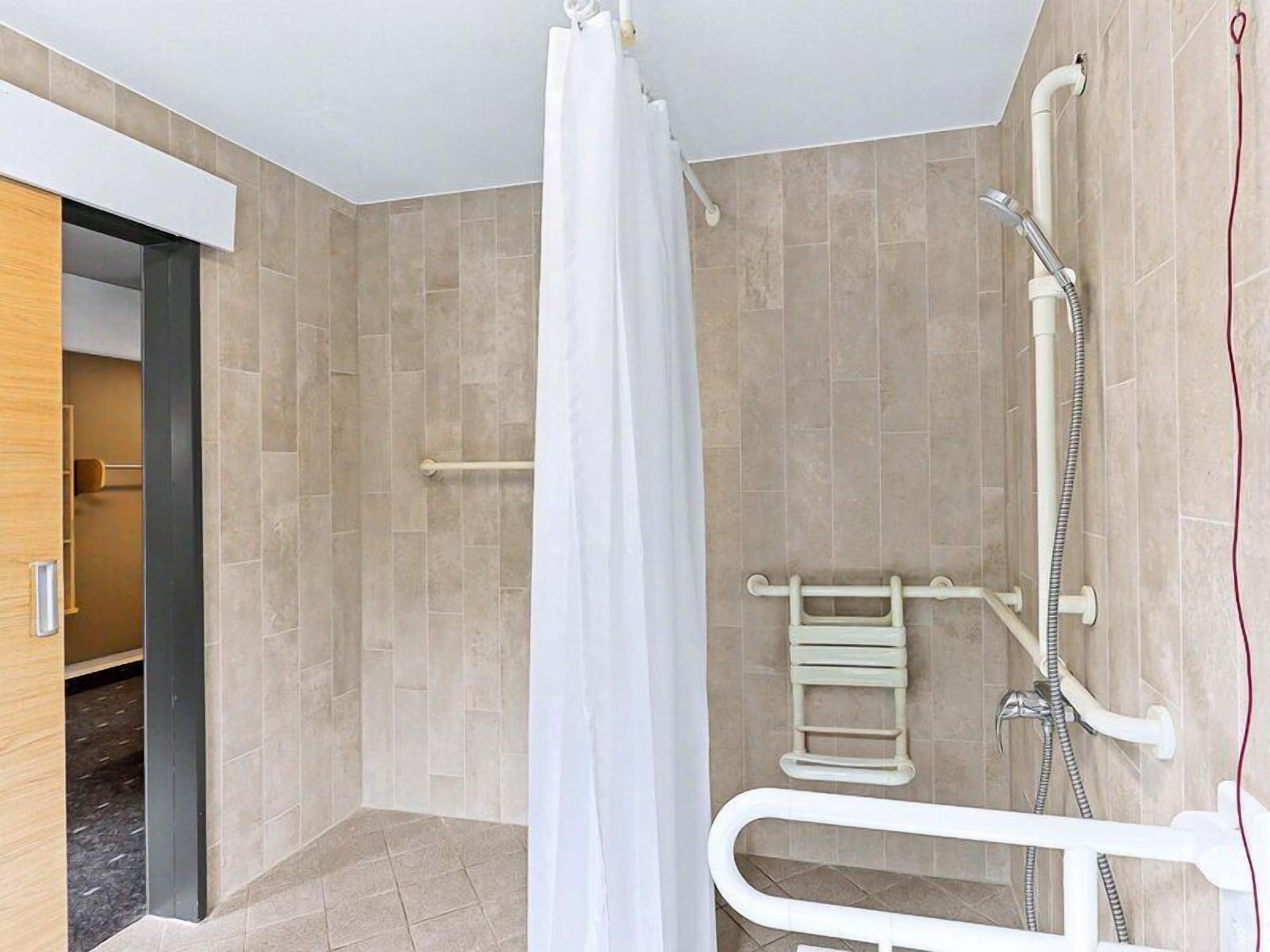Un bagno moderno con doccia, maniglie di sostegno e portasci.