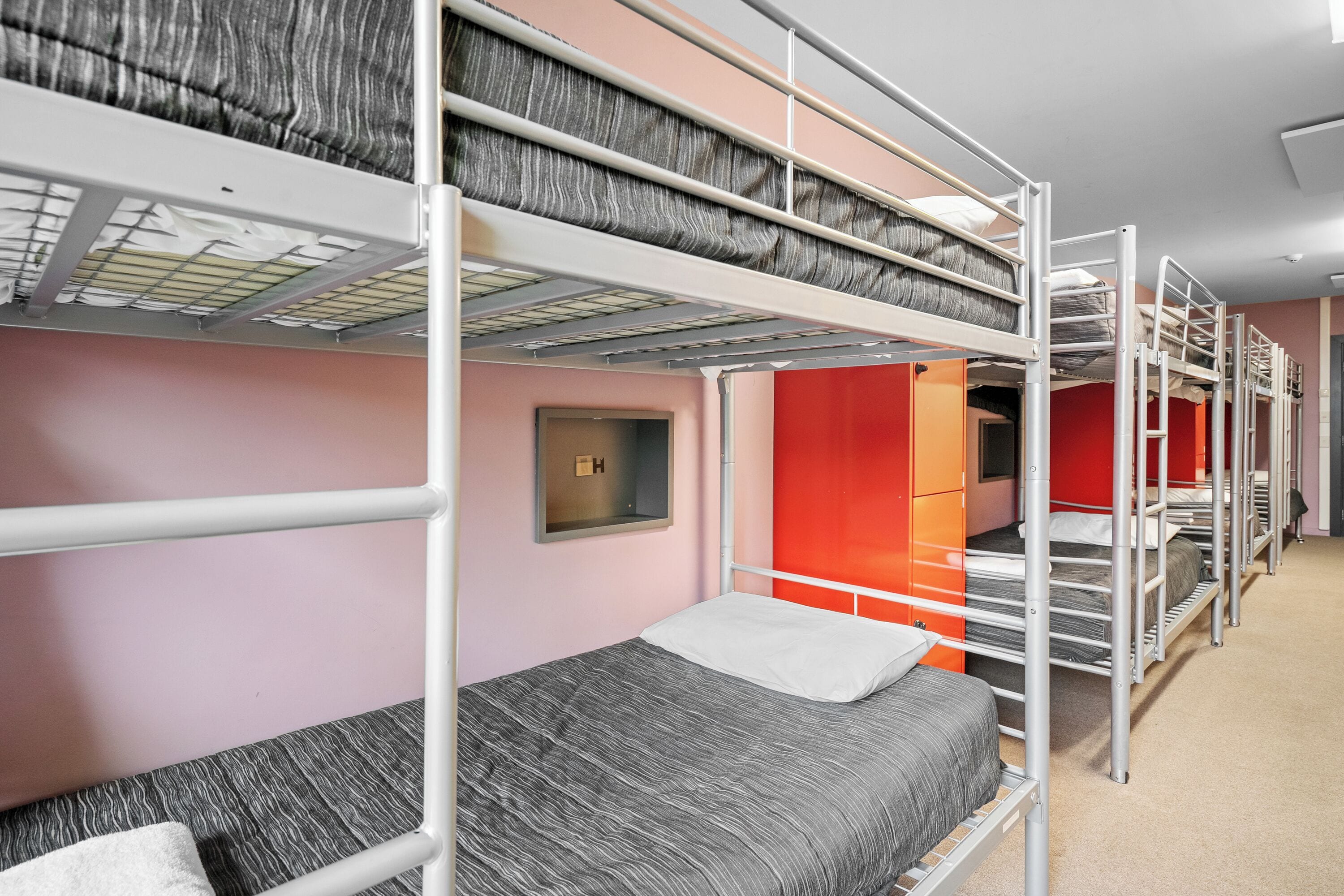 Een slaapkamer met stapelbed, een rode muur en een klein raam.
