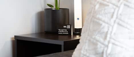 A bedside table with a potted plant, a lamp, and a pillow.