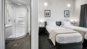 A modern hotel room with a curved shower enclosure, two beds with white linens, a wooden ceiling, and framed pictures on the wall. - Bealey Quarter (Christchurch)