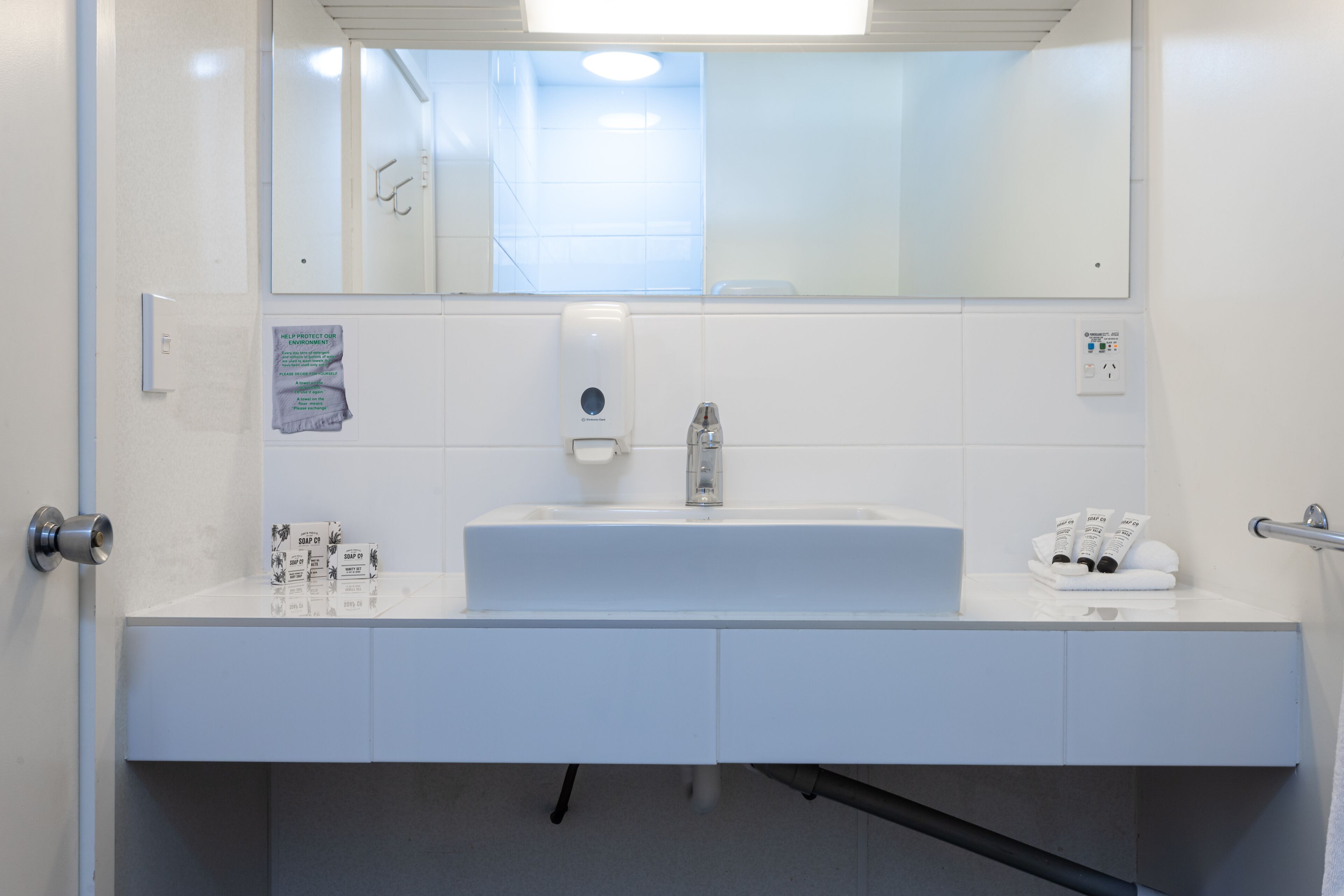 A modern bathroom with a white sink, mirror, and towel rack.
