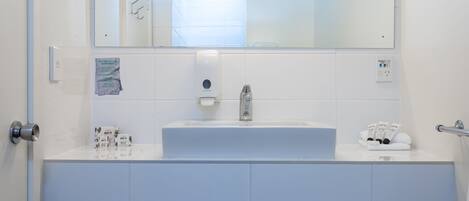 A modern bathroom with a white sink, mirror, and towel rack.