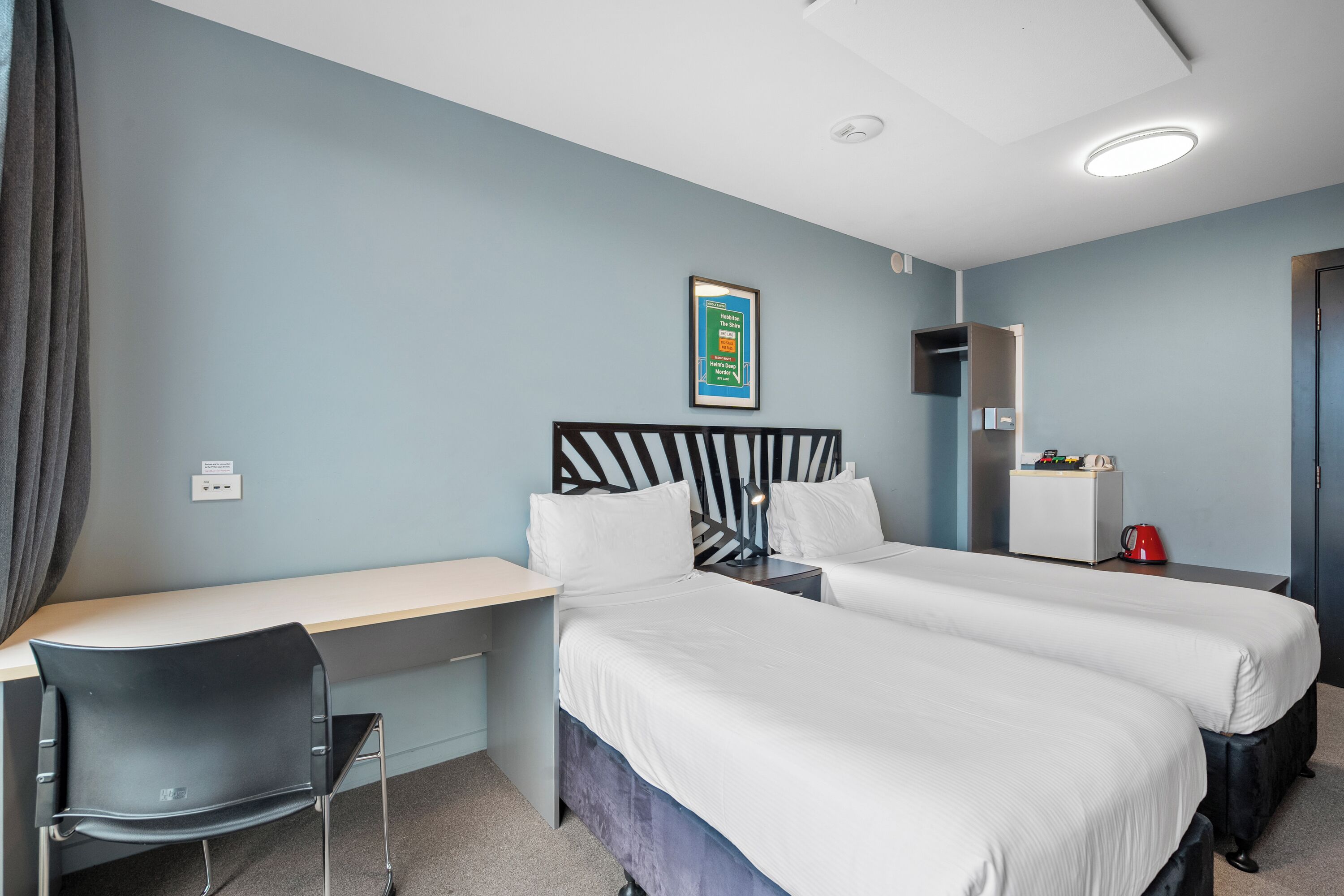 Ein Hotelzimmer mit zwei Betten, einem Schreibtisch und einem Stuhl.