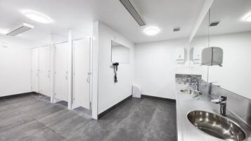 A modern restroom with multiple sinks, a hand dryer, and a mirror.