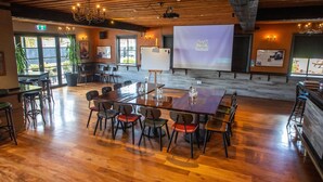 A spacious room with a large wooden table and chairs, a projector screen, and a whiteboard. - Bealey Quarter (Christchurch)