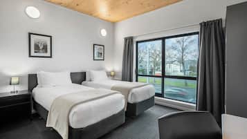 A hotel room with two beds, a large window with curtains, a desk, and a chair.