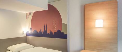 Habitación de hotel con cama, repisa montada en la pared y un mural con vista a la ciudad.