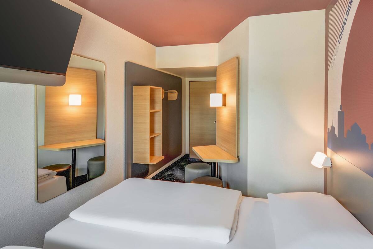 Ein Hotelzimmer mit Bett, Schreibtisch, Stuhl und Spiegel.