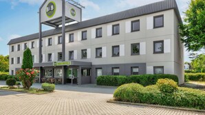 A B&B hotel with a modern design, featuring a central entrance, multiple windows, and a well-maintained garden area. - B&B HOTEL Kassel-Lohfelden (Lohfelden)