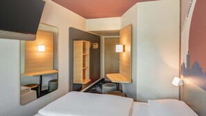 A hotel room with a bed, a desk, a chair, and a mirror. - B&B HOTEL Kassel-Lohfelden (Lohfelden)