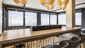 A conference room with a long table, chairs, and large windows with blinds.