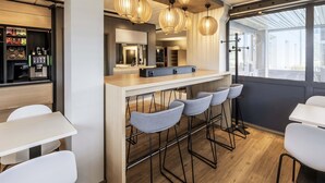 Un área de bar moderna con una barra de madera, taburetes y lámparas colgantes.