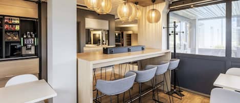 A modern bar area with a wooden counter, bar stools, and pendant lighting.