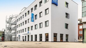 Un edificio moderno con varias ventanas y un llamativo letrero de 'ibis budget'.