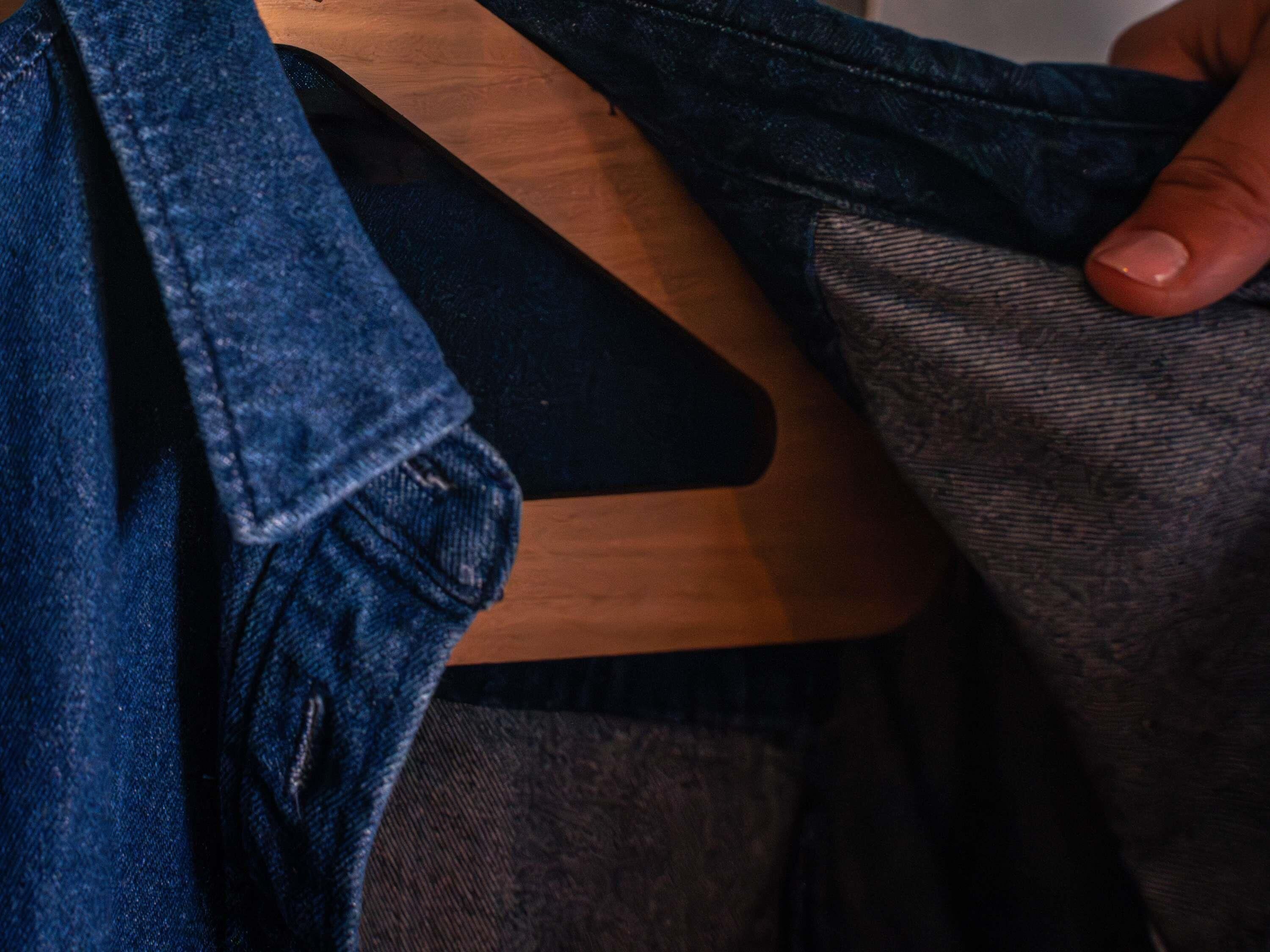 A wooden hanger with a dark fabric item on it.