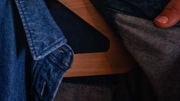 A wooden hanger with a dark fabric item on it.