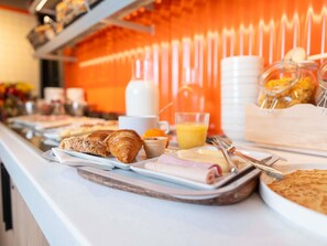 Un bufé de desayuno con diversas opciones de comida y un dispensador de zumo.