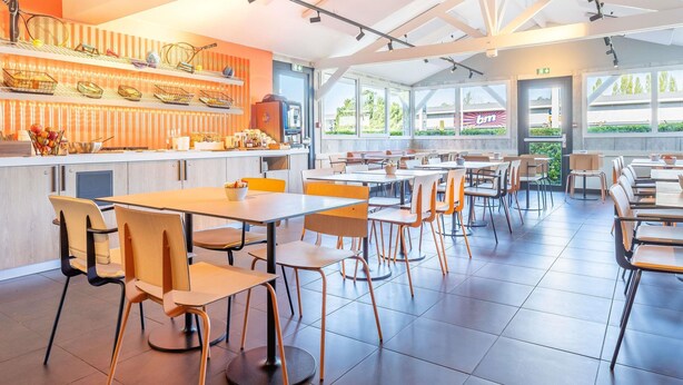 Un restaurante moderno con un interior luminoso, una barra con diferentes productos alimenticios y vistas al exterior a través de amplios ventanales.