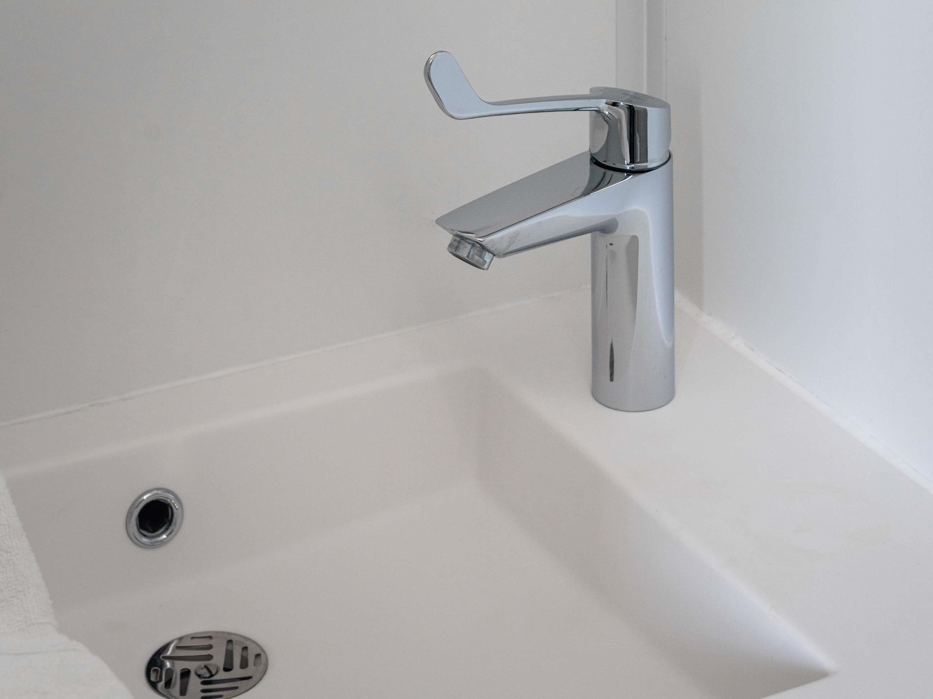 Une salle de bain moderne avec un robinet chromé, une baignoire blanche et un drain.