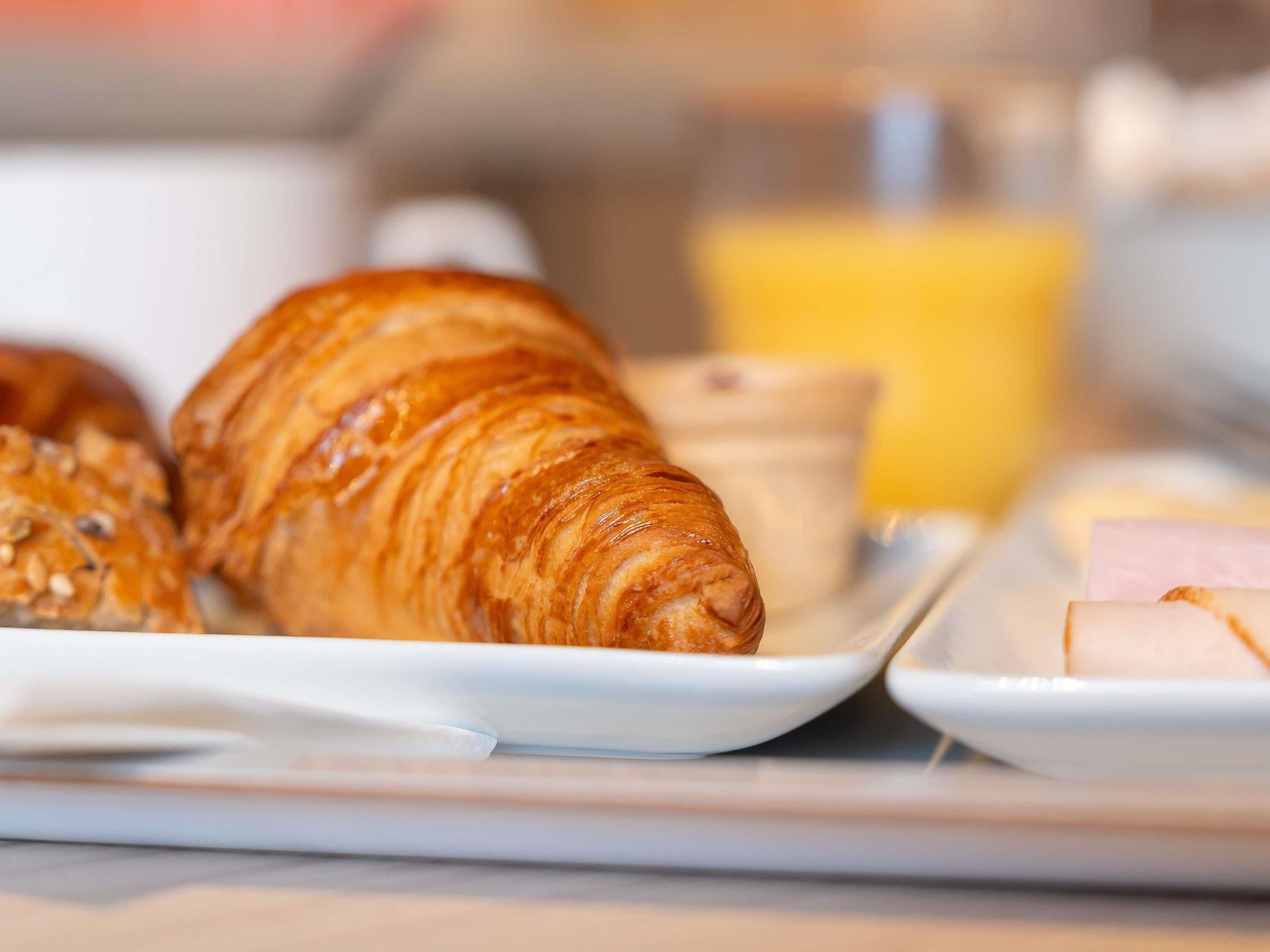 A breakfast setting with croissants, a small bowl, and a glass of orange juice.