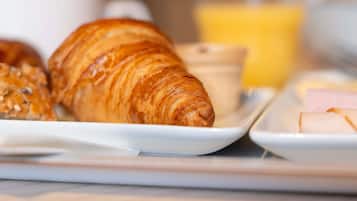 A breakfast setting with croissants, a small bowl, and a glass of orange juice.