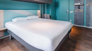 Una habitación de hotel moderna con una litera, un armario con espejo y un proyector instalado en el techo.