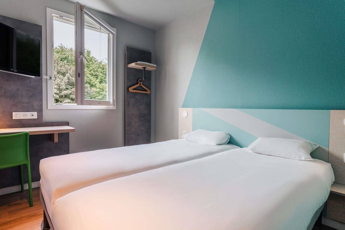 Una habitación de hotel moderna con dos camas, un escritorio y una ventana.