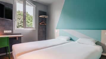 Une chambre d’hôtel moderne avec deux lits, un bureau et une fenêtre.