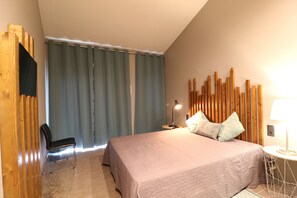 A bedroom with a bed, a chair, a nightstand, and a lamp. - Lost & Found - Guesthouse & Suites (Albufeira)