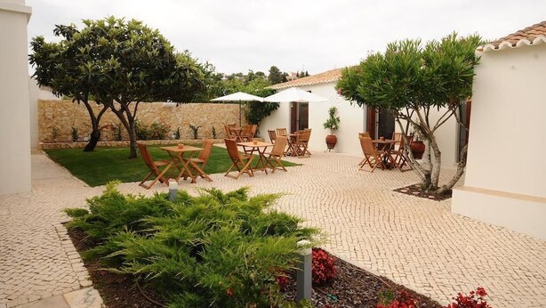 A courtyard with outdoor seating, a stone wall, and potted plants. - Lost & Found - Guesthouse & Suites (Albufeira)