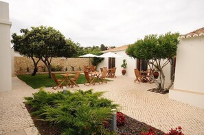 A courtyard with outdoor seating, a stone wall, and potted plants. - Lost & Found - Guesthouse & Suites (Albufeira)