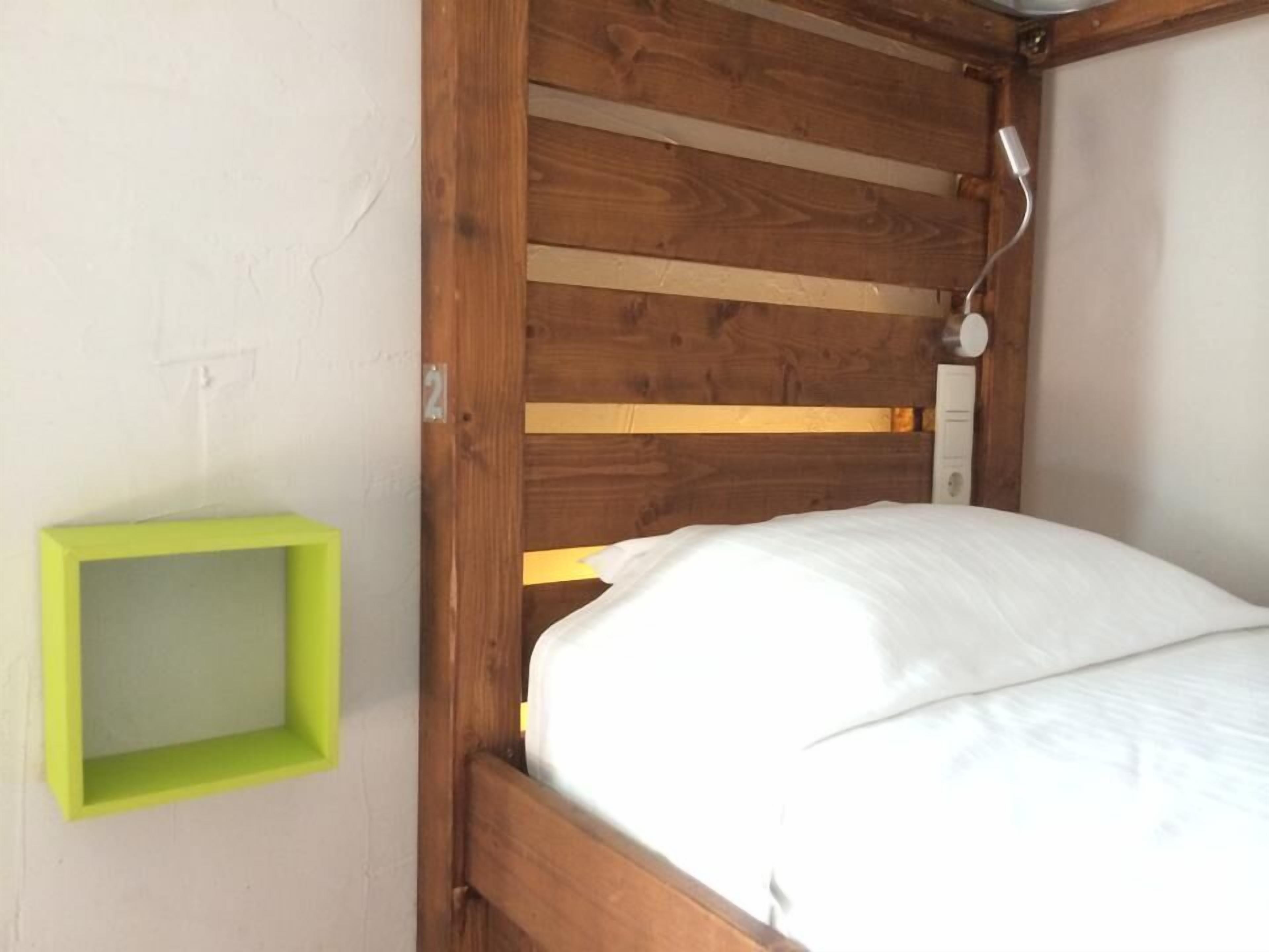 Una cama individual con cabecera de madera y estante con marco verde.