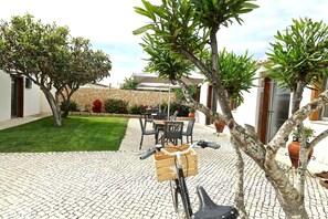 A courtyard with a bicycle, potted plants, and outdoor furniture. - Lost & Found - Guesthouse & Suites (Albufeira)