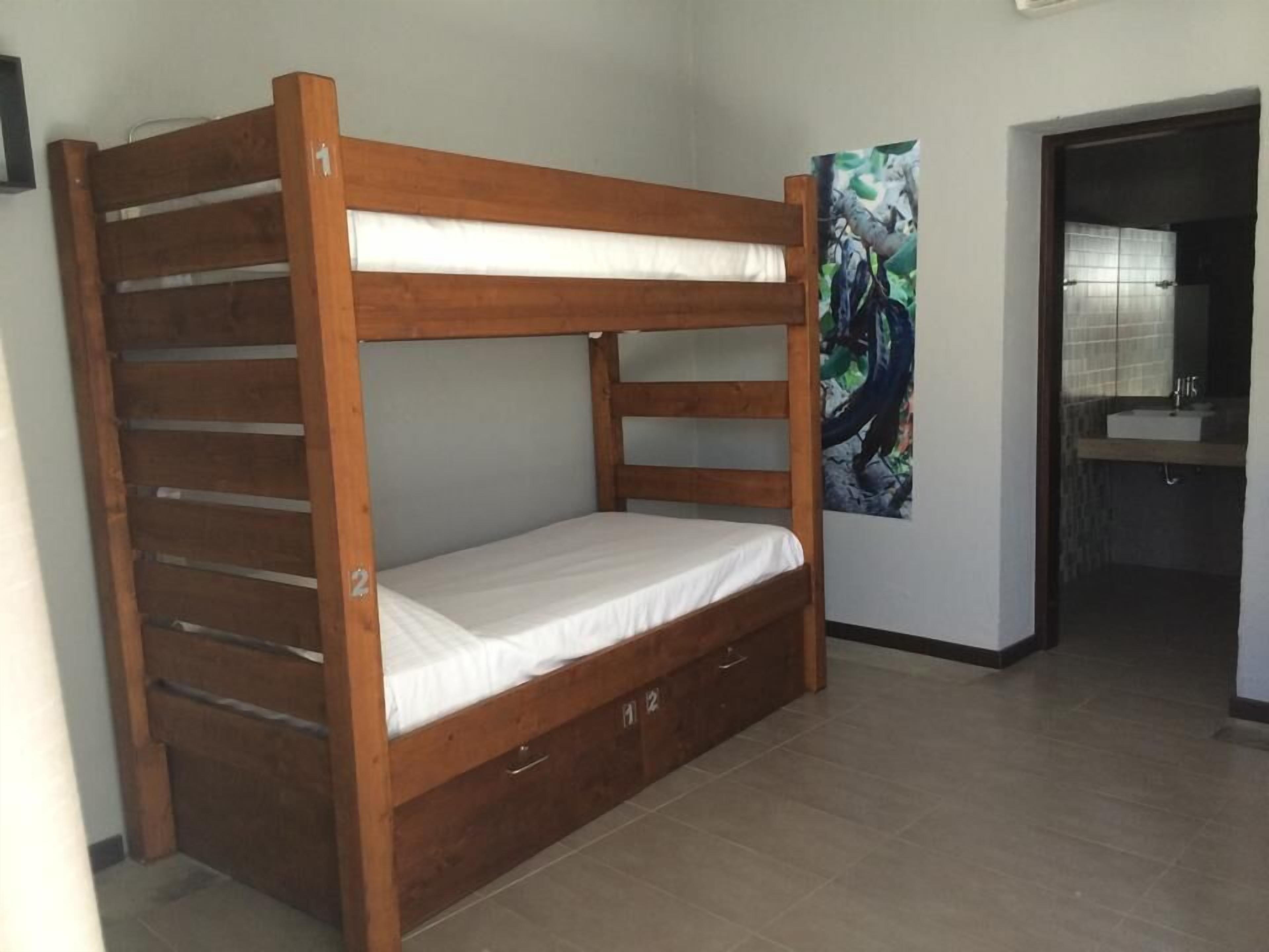 A bunk bed with a wooden frame and white bedding in a room with tiled flooring.