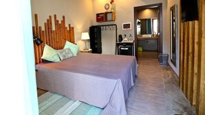 A bedroom with a bed, bedside table, lamp, and a wooden headboard. There is a bathroom visible through an open door. - Lost & Found - Guesthouse & Suites (Albufeira)