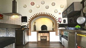A kitchen with a brick fireplace, modern appliances, and a tiled backsplash. - Lost & Found - Guesthouse & Suites (Albufeira)