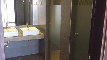 Un baño moderno con dos lavamanos, un espejo grande y una ducha a ras de suelo.