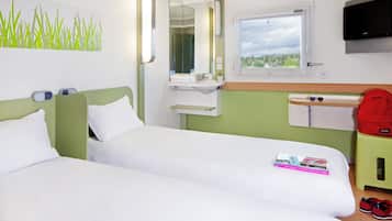 A hotel room with two beds, a bathroom with a mirror, a window, and a television.