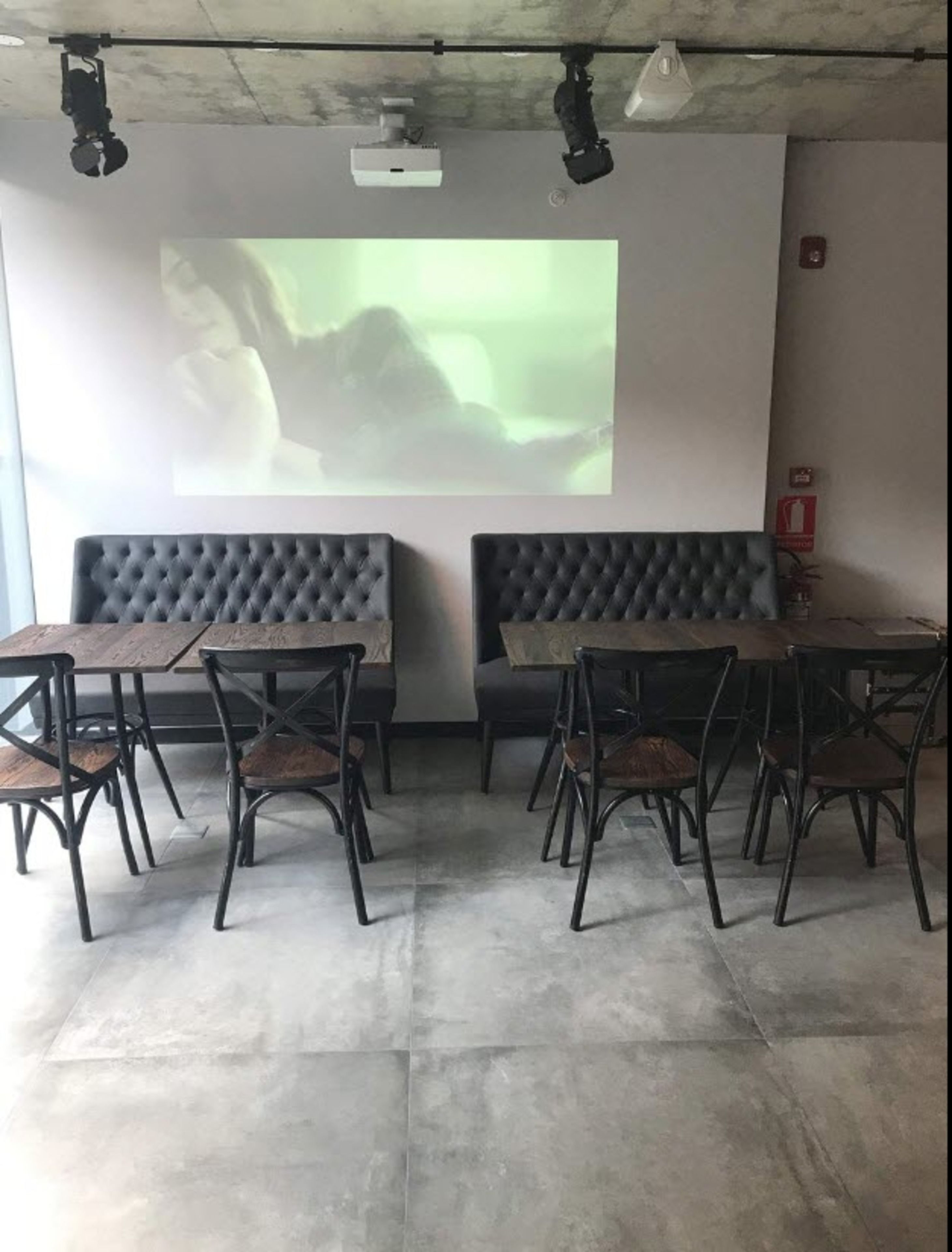 A conference room with a large screen displaying a presentation, a sofa, and a dining table with chairs.