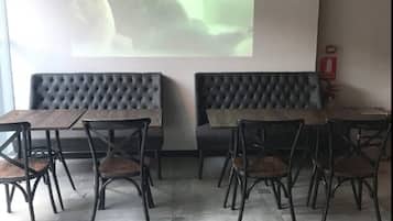 A conference room with a large screen displaying a presentation, a sofa, and a dining table with chairs.