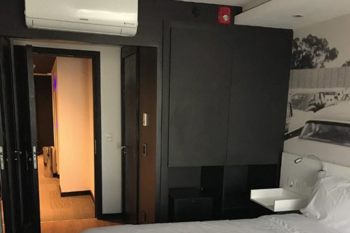 Habitación de hotel con dos camas, un armario, un escritorio y un aire acondicionado.