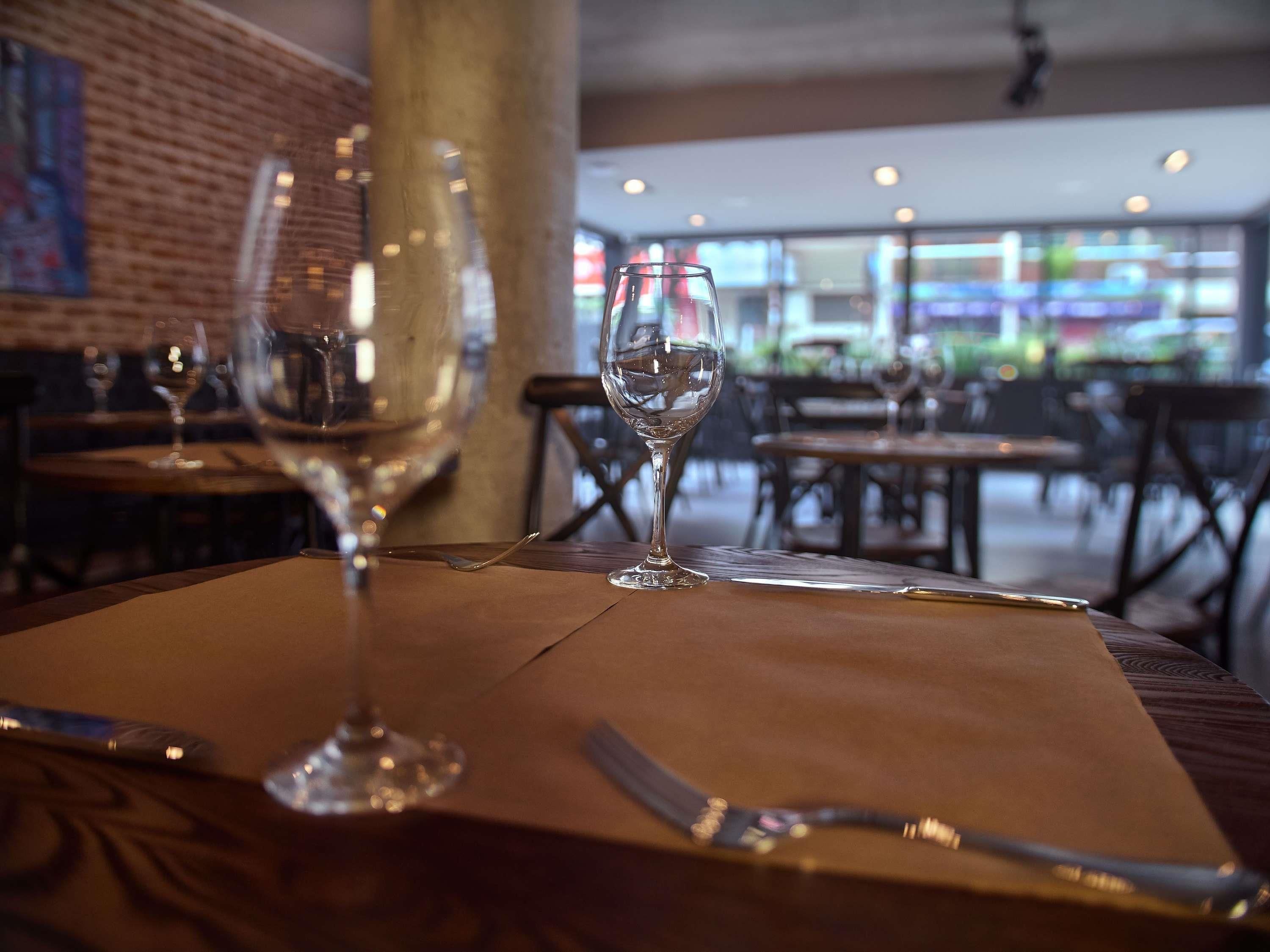 Een restaurantinterieur met gedekte tafels, met helder glaswerk en bestek.