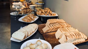 Un bufé con diversas opciones de pan y pastelería, incluyendo cruasanes, baguettes y bollos.