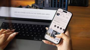 Una computadora portátil muestra una página de reserva de hotel, con vista a un edificio, y un teléfono inteligente con una interfaz de reservas.