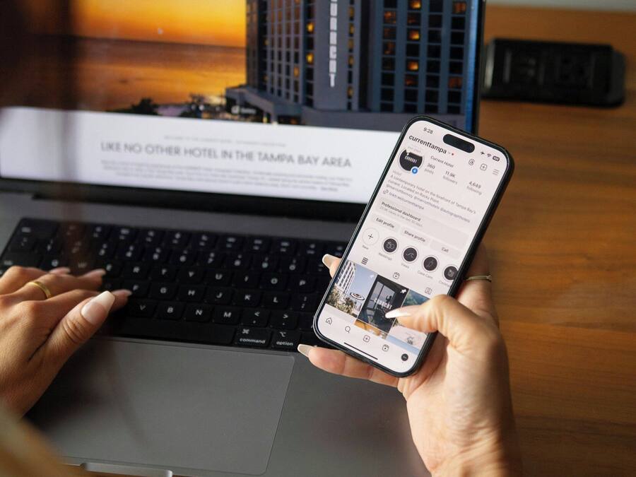 Una computadora portátil muestra una página de reserva de hotel, con vista a un edificio, y un teléfono inteligente con una interfaz de reservas.